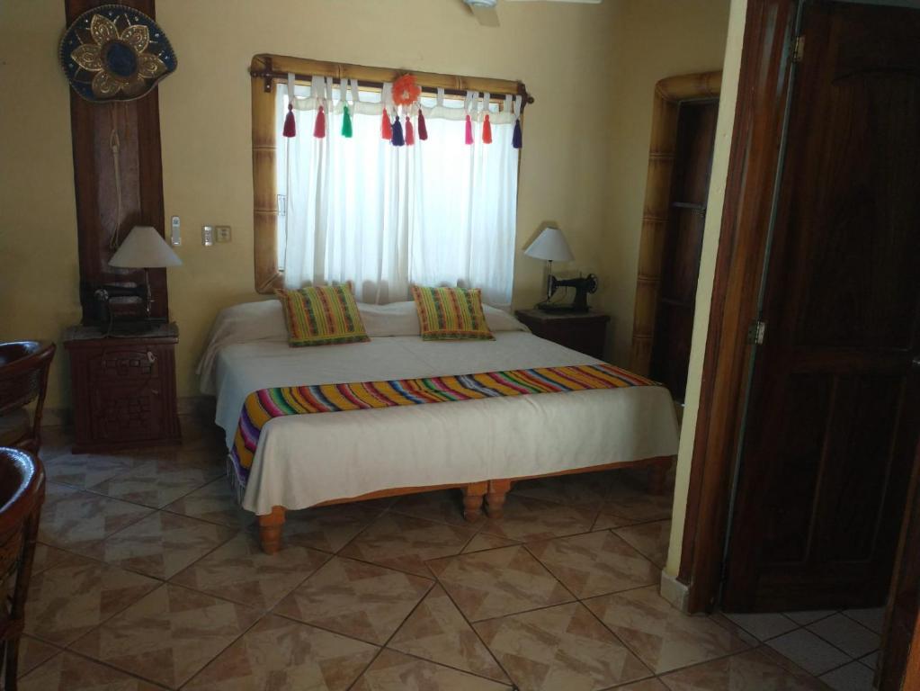 a bedroom with a large bed with a window at Hacienda Jaqueline in Sayulita