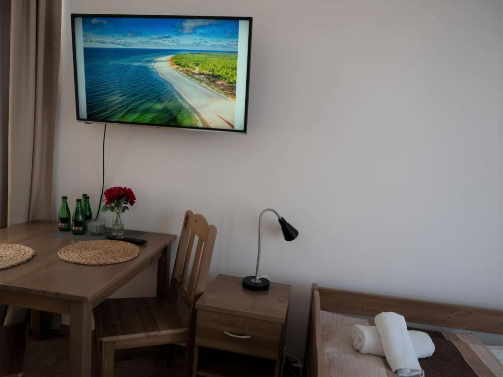 jadalnia ze stołem i telewizorem na ścianie w obiekcie Planeta Apartment Mielno w mieście Mielno