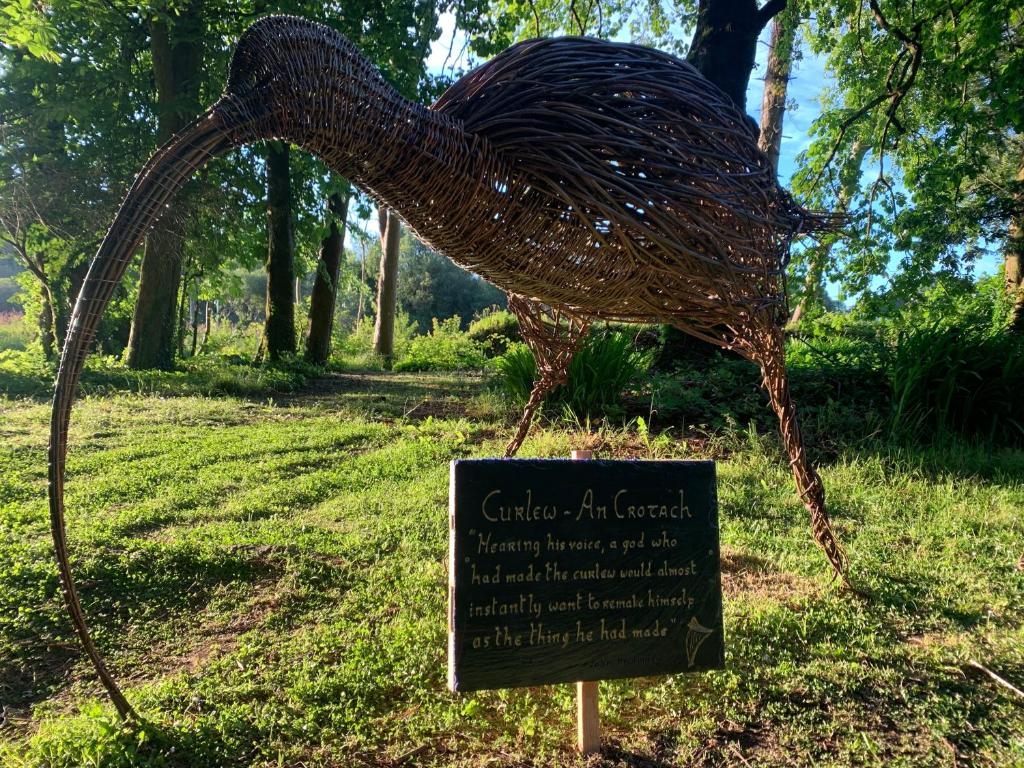 a statue of a bird with a sign in the grass at Ryan's River Lodge B&B in Cong
