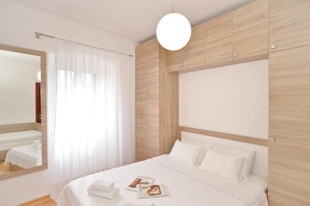 a bedroom with a white bed and a mirror at Sofija Apartment in Kotor