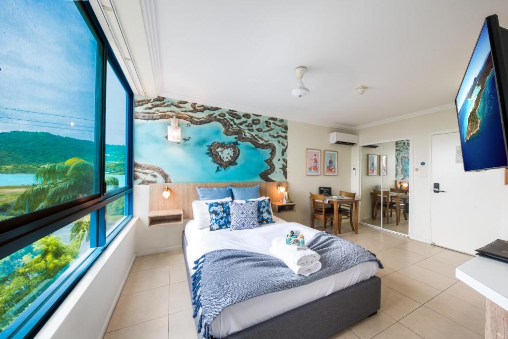 una camera da letto con un letto e una grande finestra di ☆Airliedise☆HOT TUB suite☆5min walk 2 Port of Airlie/Ferry terminal☆WiFi☆Netflix☆NO Hills ad Airlie Beach