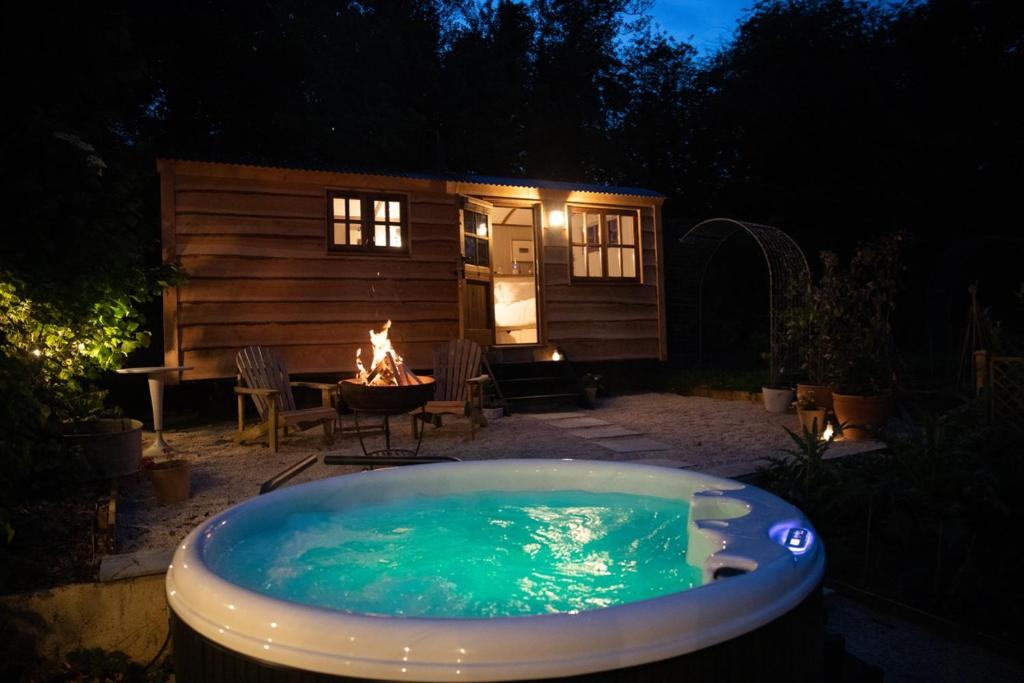 a hot tub in front of a cabin with a fireplace at Luxury, rural Shepherds Hut with hot tub nr Bath in Bristol