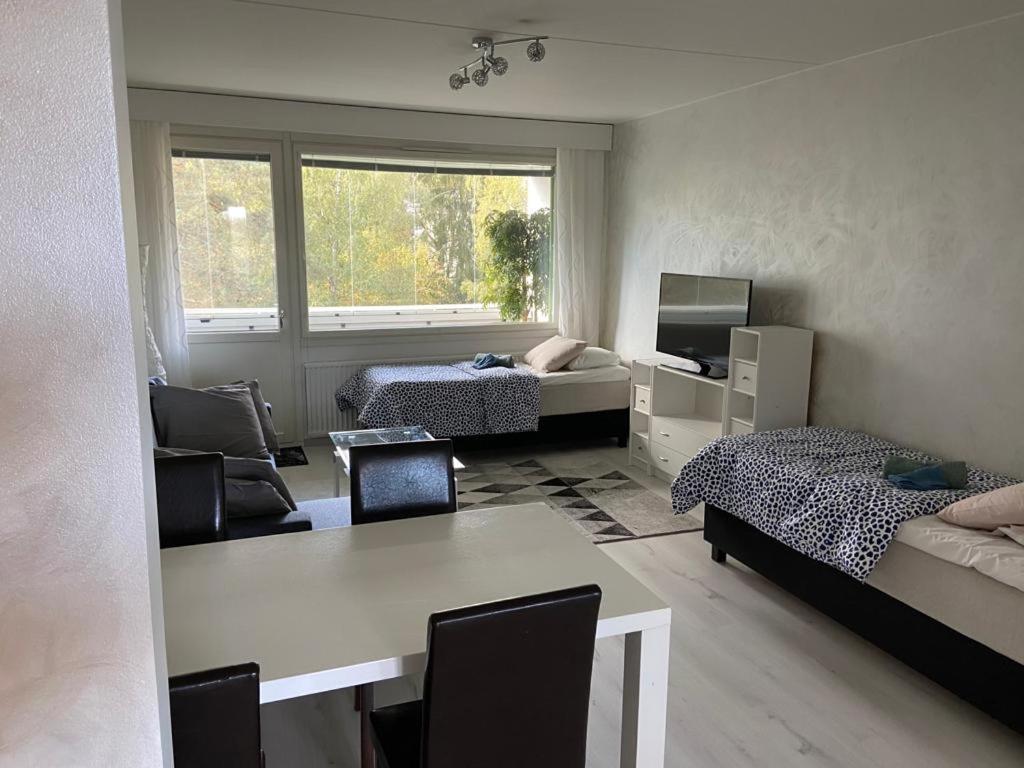 a room with two beds and a table with a desk at M Apartments Tesomankuja in Tampere
