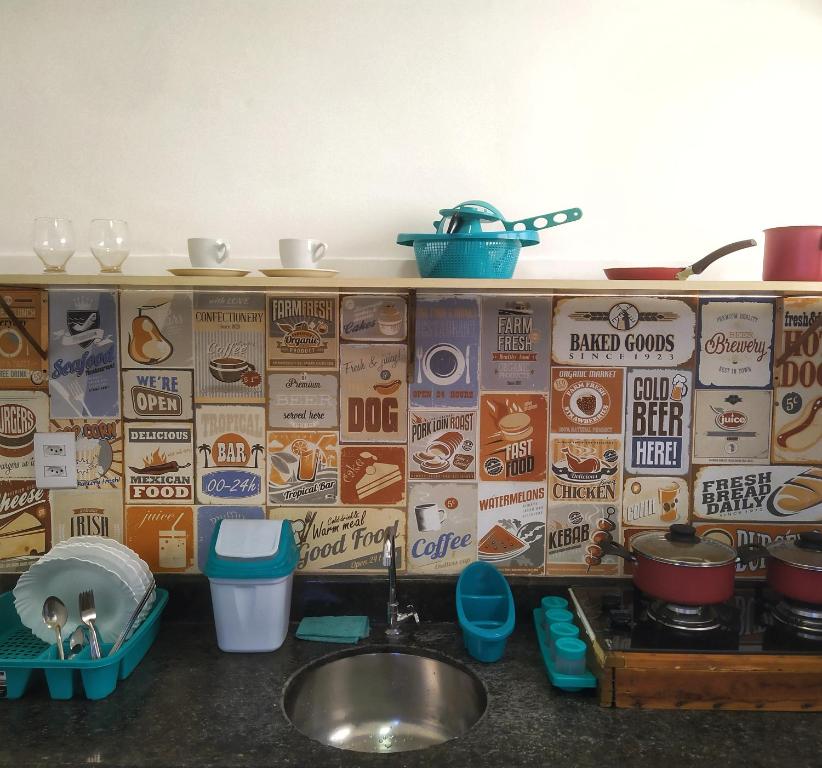 a kitchen counter with a sink and a wall with advertisements at Studio 2 em Itapuã 900m da praia! in Salvador