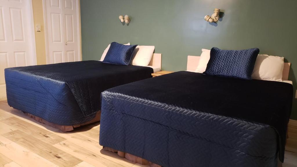 two beds with blue covers in a room at Oakwood Motel in Gravenhurst