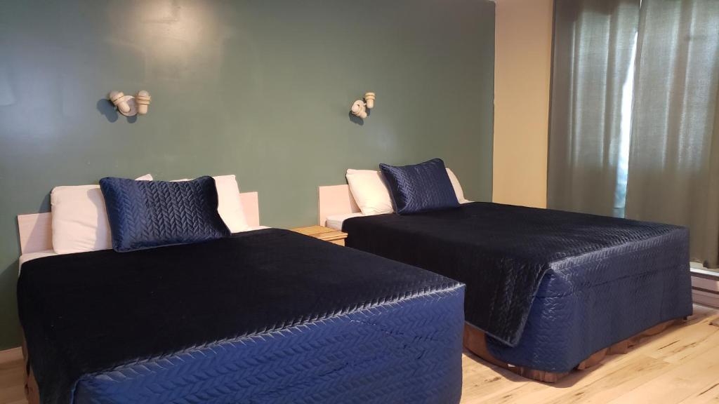 two beds in a room with blue sheets and pillows at Oakwood Motel in Gravenhurst