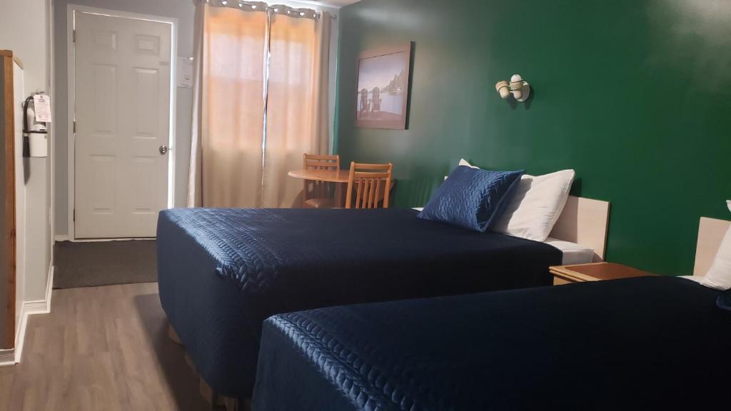 a bedroom with two beds and a green wall at Oakwood Motel in Gravenhurst