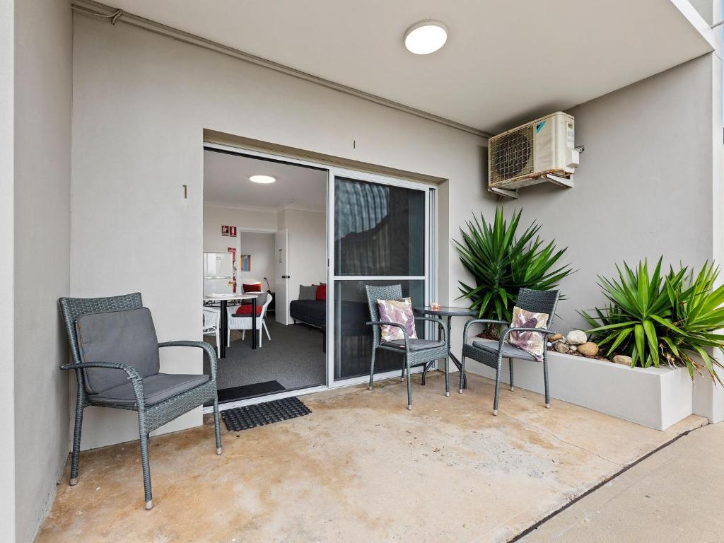 
a patio area with chairs, a table and a window at Golfers Lodge Unit 1 in Narooma
