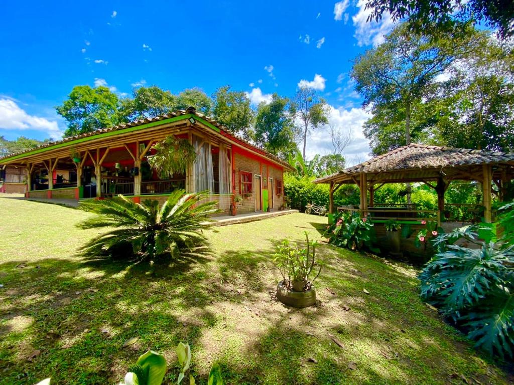 una casa roja con un pabellón en un patio en Finca Hotel Cabaña Fercho, en Quimbaya