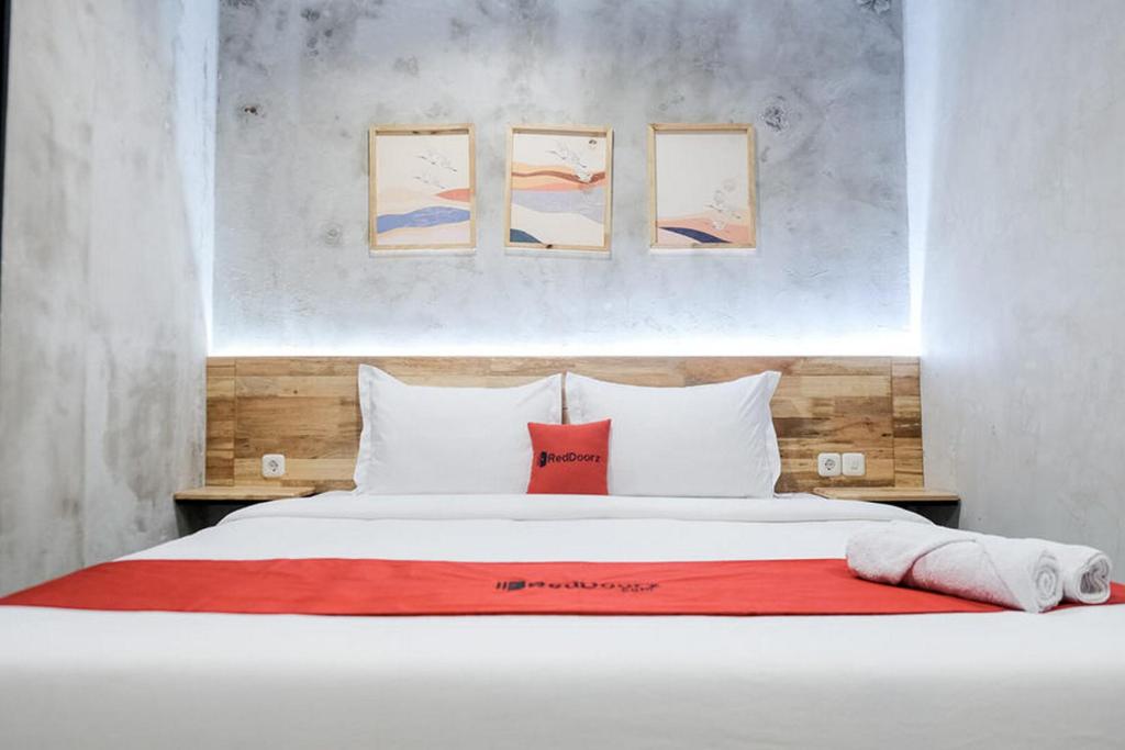 a bedroom with a white bed with a red blanket on it at RedDoorz @ Sekip Medan in Medan