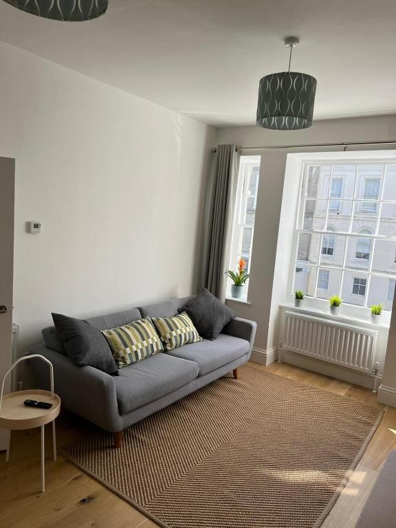 un salon avec un canapé et deux fenêtres dans l'établissement Lovely 1 Bed flat *FREE PARKING* Hoe/Barbican Plymouth, à Plymouth