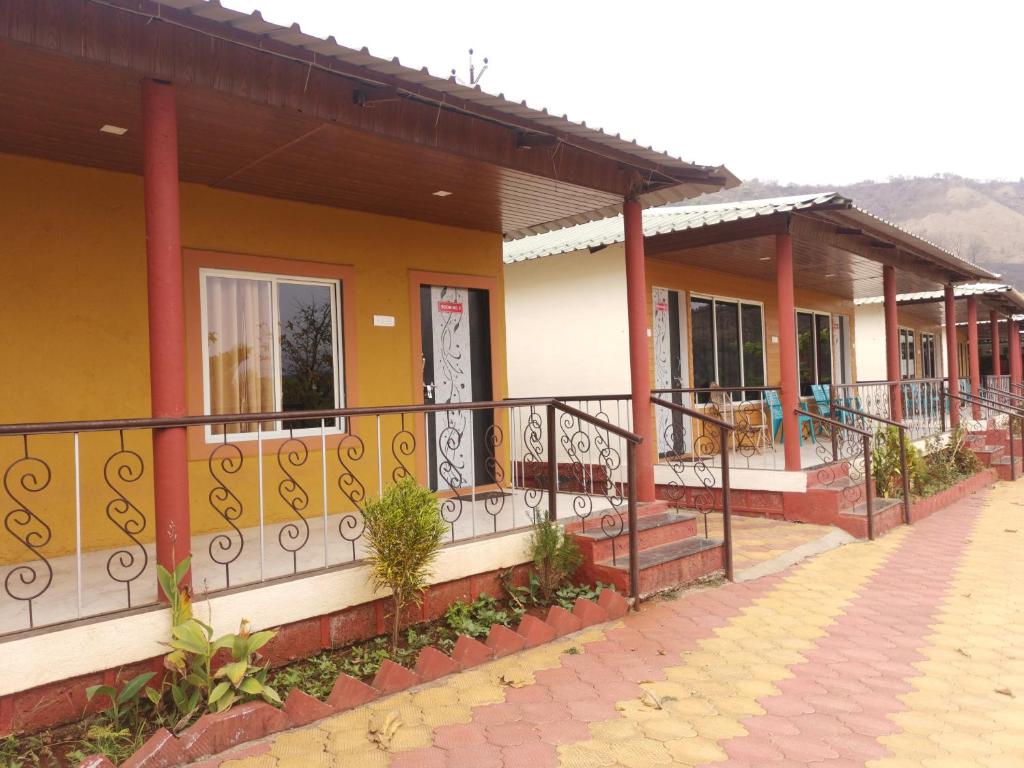 eine Reihe von Häusern mit Balkon auf einer Straße in der Unterkunft Shivshrushti Agro Tourism & River Camp Tapola in Mahabaleshwar