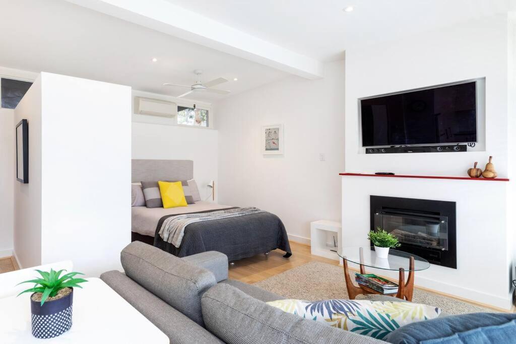 een woonkamer met een bank en een open haard bij Modern Stylish Self-contained Studio Apartment in Burnside