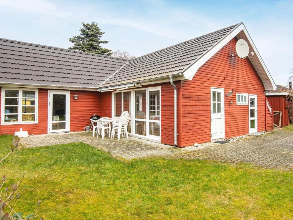 a red house with a table and chairs in a yard at Holiday home Grenaa VI in Grenå