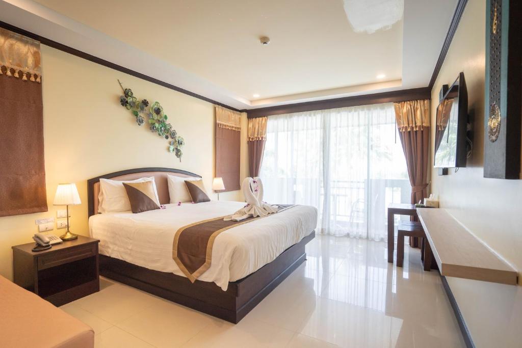 a bedroom with a bed and a desk and a window at Baan Sailom Hotel Phuket - Sha Extra Plus in Karon Beach