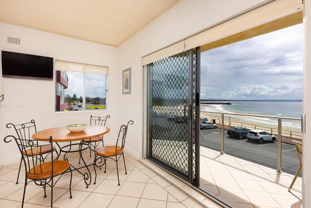 ein Balkon mit Tisch und Stühlen und Blick auf das Meer in der Unterkunft At the Beach, Debra Court Unit 5 in Forster