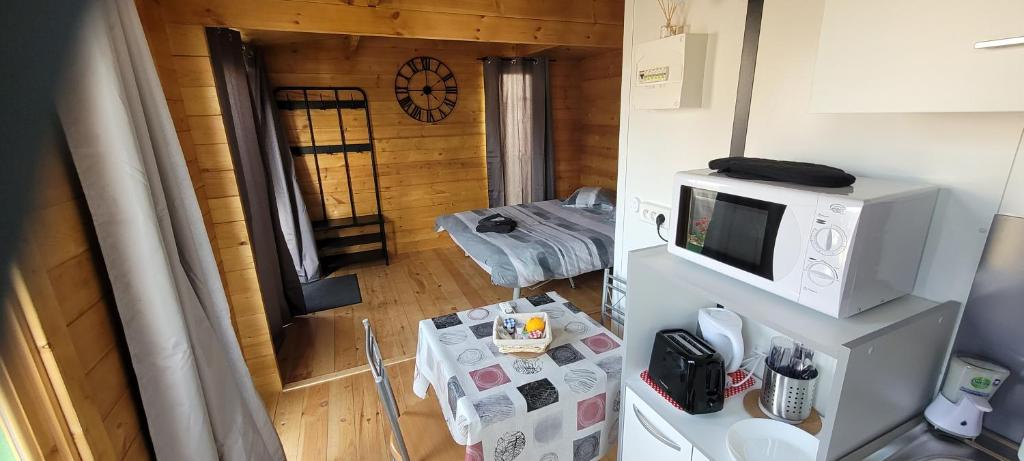 Zimmer mit einer Mikrowelle und einem Zimmer mit einem Tisch in der Unterkunft Chalet piscine montech in Montech