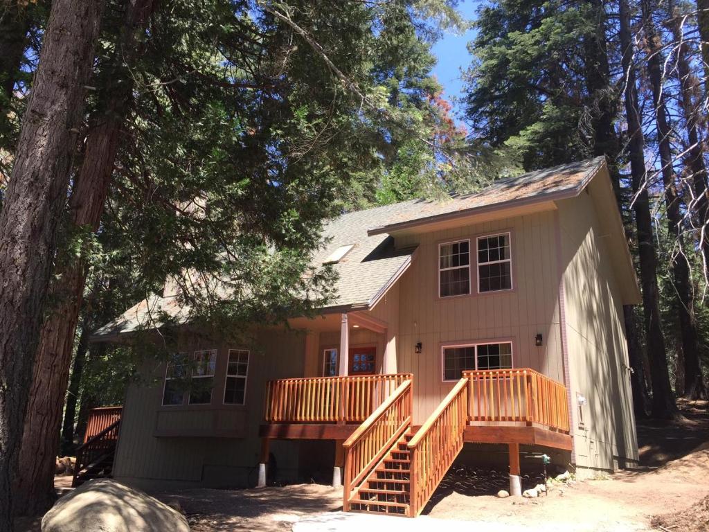 a small house with a deck in the woods at Alder Lodge in Yosemite West