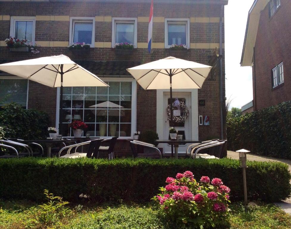 deux tables et chaises avec parasols devant un bâtiment dans l'établissement Hotel Pension Oranje, à Fauquemont