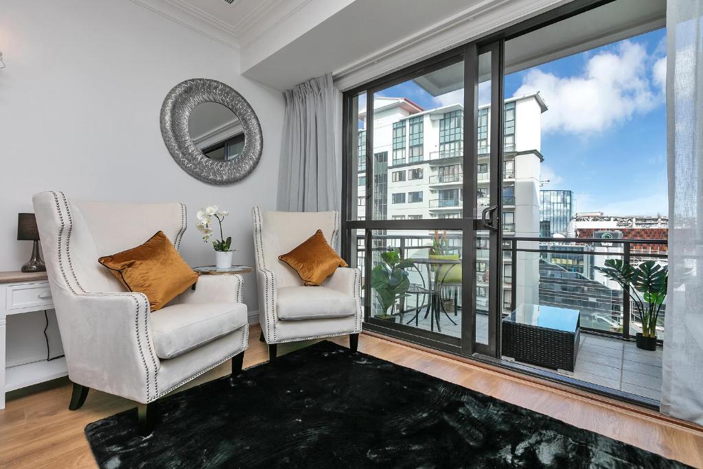 a living room with two chairs and a large window at Sky Tower Serenity + Rooftop Pool in Auckland