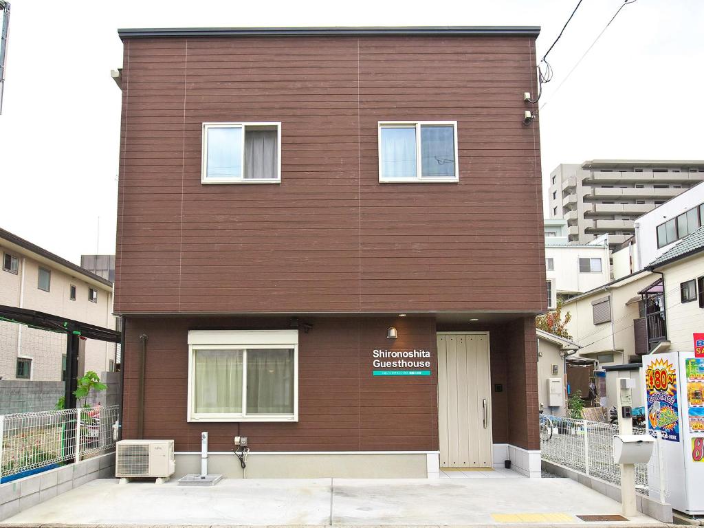 ein braunes Backsteingebäude mit einem Schild darauf in der Unterkunft Shironoshita Guesthouse in Himeji