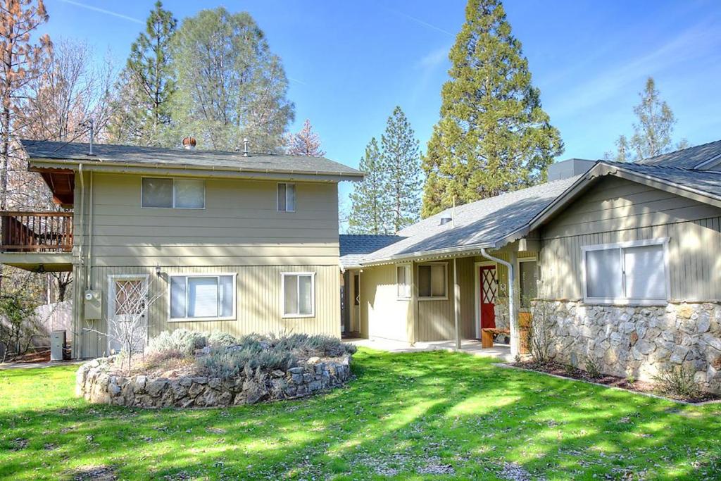 a house with a stone wall in a yard at Lazy Bear Lodge in Oakhurst