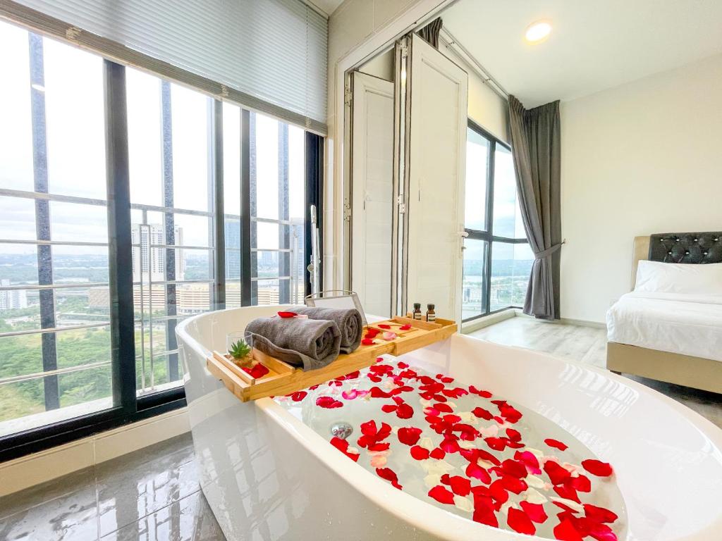 La salle de bains est pourvue d'une baignoire avec des roses rouges. dans l'établissement Midvalley Southkey Mosaic Suite by Nest Home, à Johor Bahru