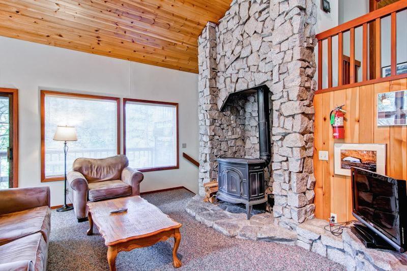 una sala de estar con chimenea de piedra en una casa en Sport Chalet, en Yosemite West