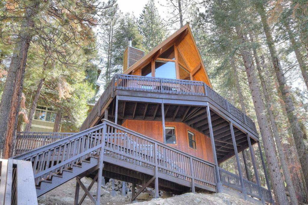 a tree house in the woods with a large deck at Treetops Cabin in Yosemite West