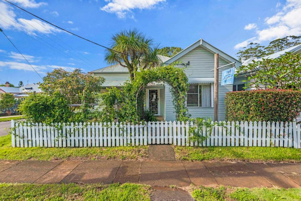 a white picket fence in front of a white house at Divine Cottage - Main Street Bangalow in Bangalow