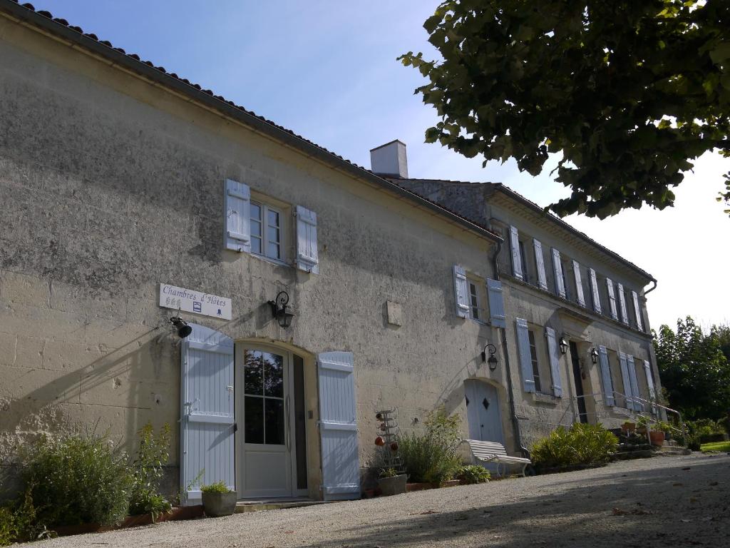 an old stone building with white doors and windows at Chambres d'Hôtes - Les Bujours in Saint-Georges-des-Côteaux