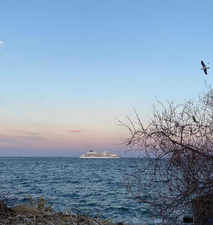 a large cruise ship in the ocean at sunset at Overwave Apartment in Kavála