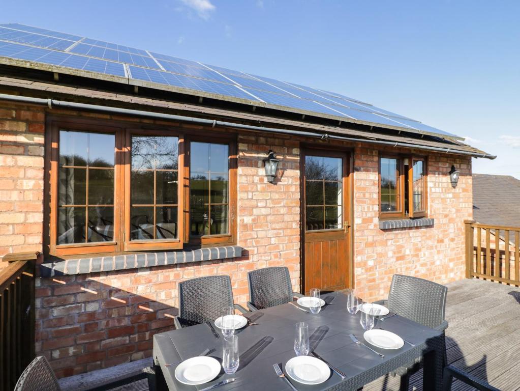 een tafel en stoelen op een patio met een huis met zonnepanelen bij Avon View in Stratford-upon-Avon