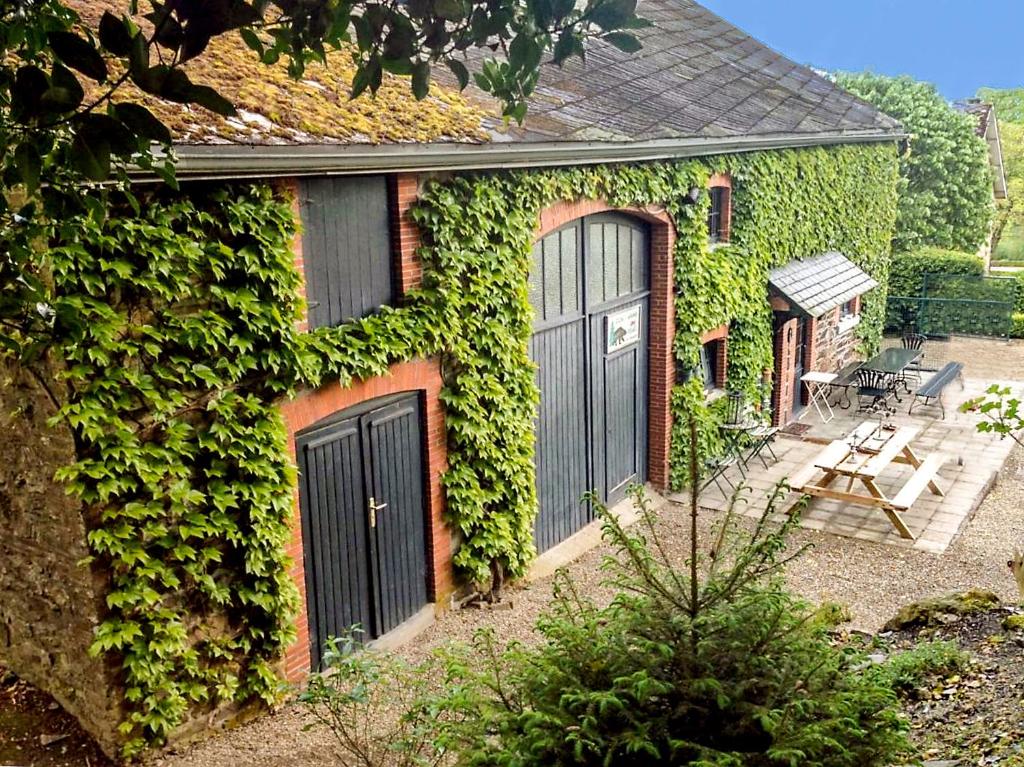 una casa cubierta de hiedra con dos puertas y un patio en Gîte La Grande Francorchamps Ardennaise, en Stavelot