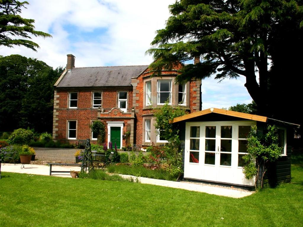 una casa de ladrillo rojo con garaje blanco en Broomhouse Farmhouse, en Cheswick