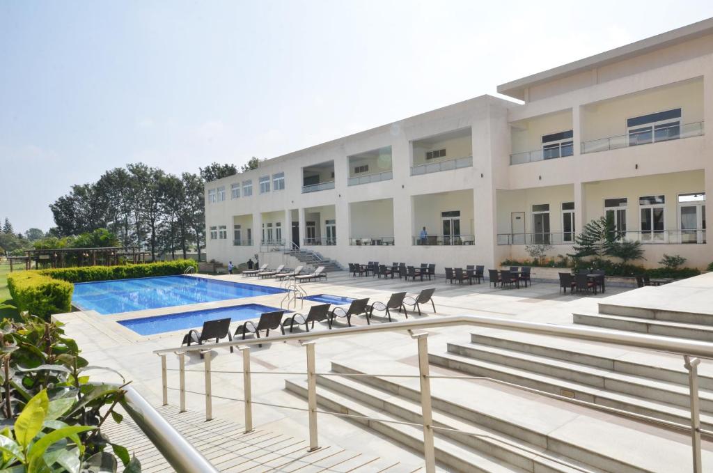 Spree Resort At Century Wintersun في Dod Ballāpur: مبنى كبير به مسبح وكراسي