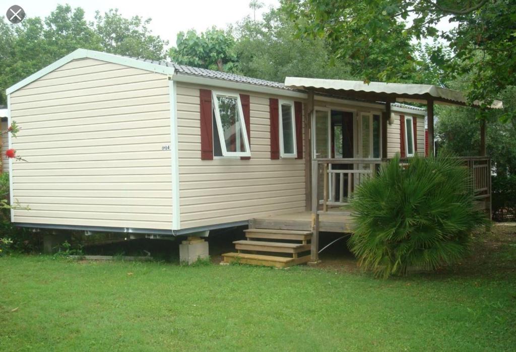 a small white house with a porch and stairs at Location Mobil Home in Vias