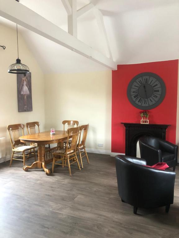 a dining room with a table and a clock on the wall at Wesley Rooms Annexe in Ironbridge