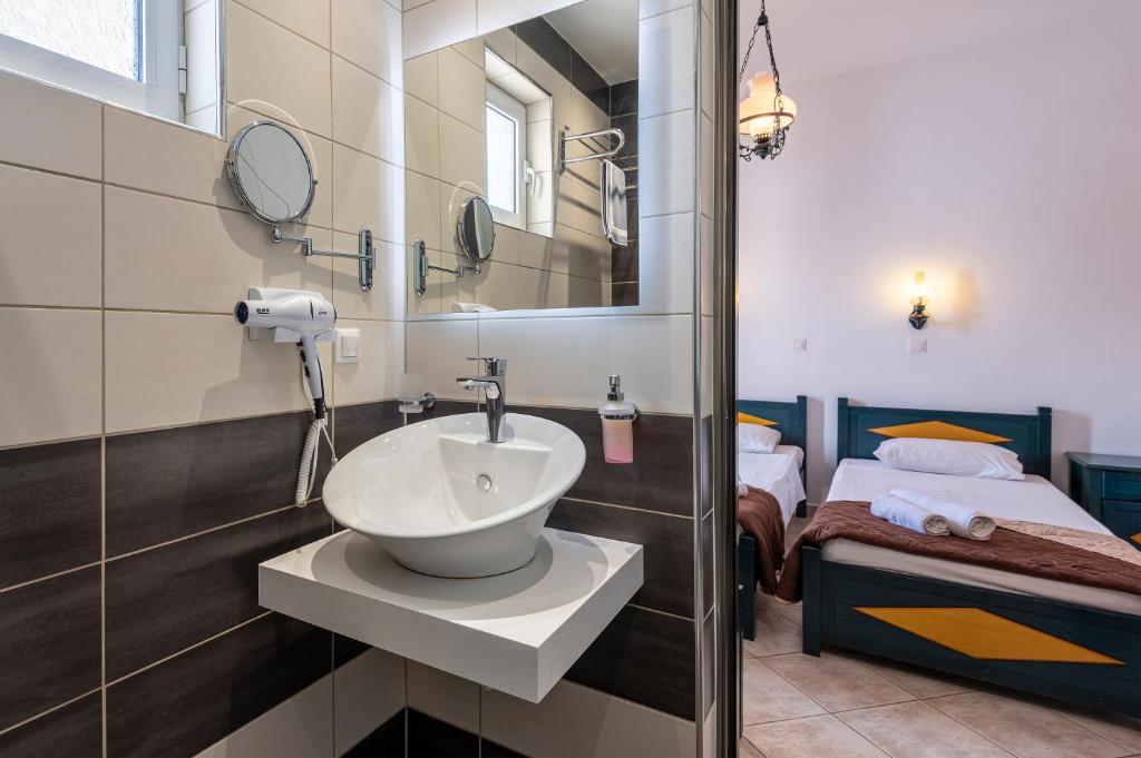 a bathroom with a sink and a mirror and a bed at Cirillo Family Hotel-Christinas Studios in Mastihari