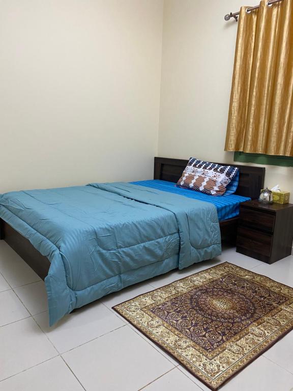 a bed with a blue comforter in a bedroom at Entire Studio Flat in Sharjah. in Sharjah