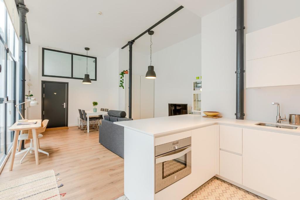 a kitchen with white cabinets and a living room at HoneyMoon Apartment in Seville