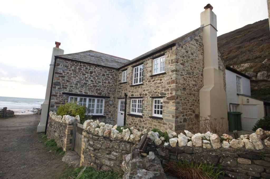 a stone house with a stone fence in front of it at Penkenna House, Crackington Haven, North Cornwall in Crackington Haven