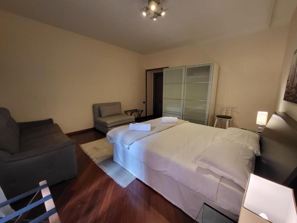 sypialnia z dużym białym łóżkiem i krzesłem w obiekcie Colosseo Homerents 2 w Rzymie