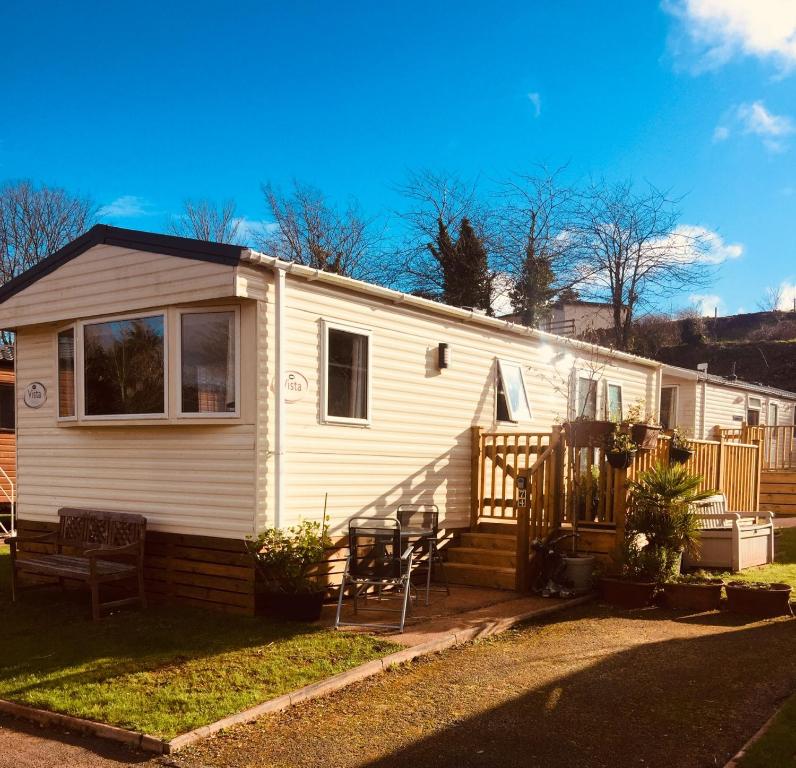 a small white house with a porch and chairs at 74, Orchard Park in Paignton