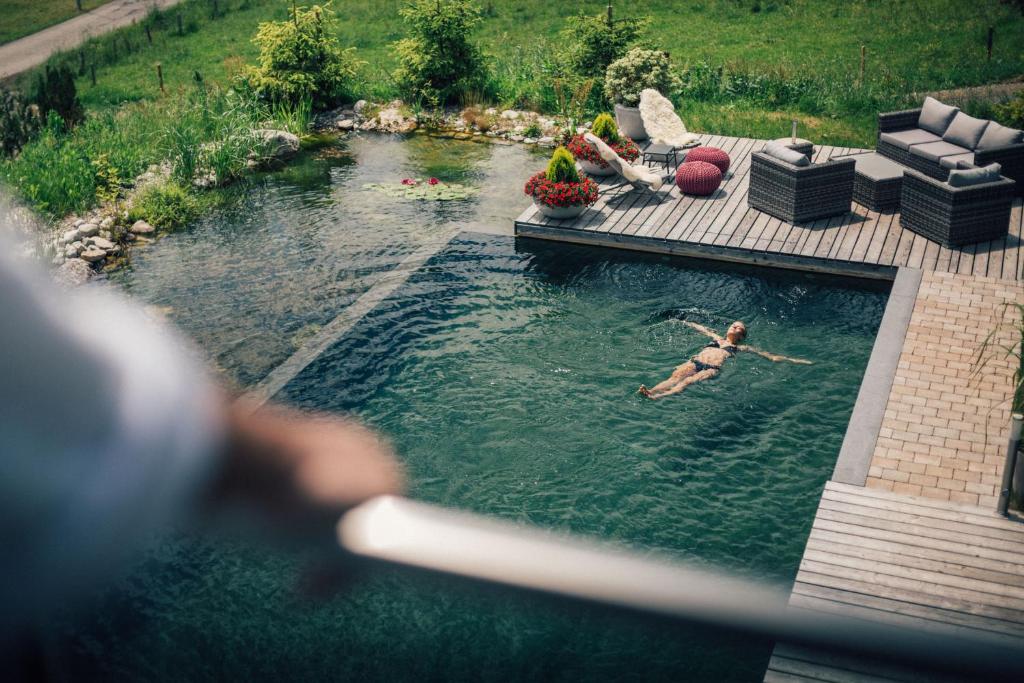 uma mulher está nadando em uma piscina de água em Torghele's Wald & Fluh em Balderschwang
