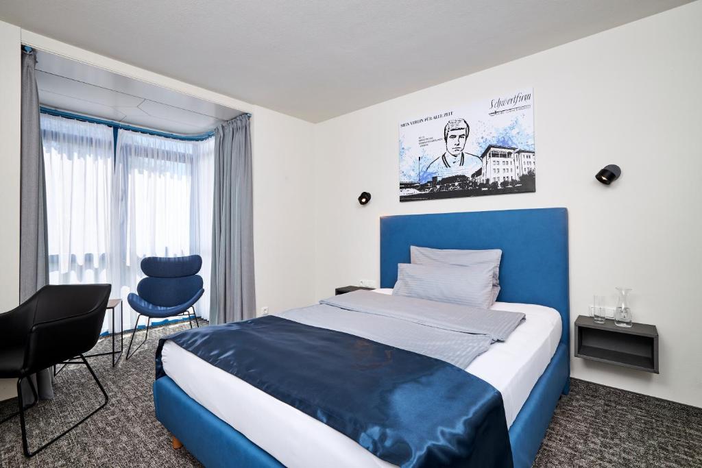 a bedroom with a blue bed and a chair at Hotel Schwertfirm in Karlsfeld