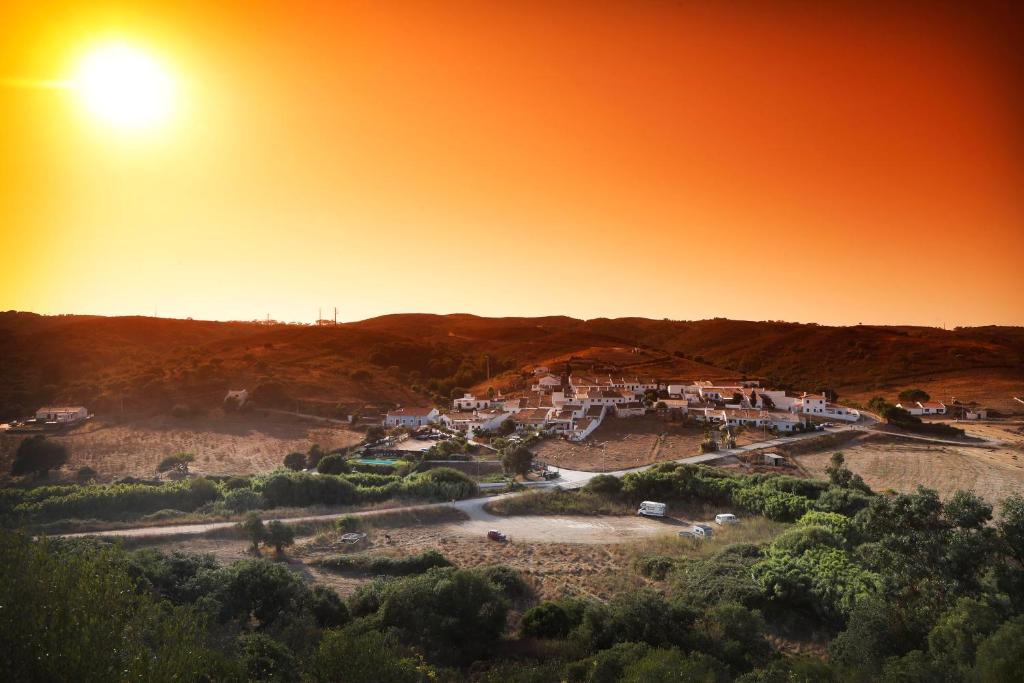 a village on a hill with the sun in the sky at Casa Amado, Aldeia da Pedralva in Vila do Bispo