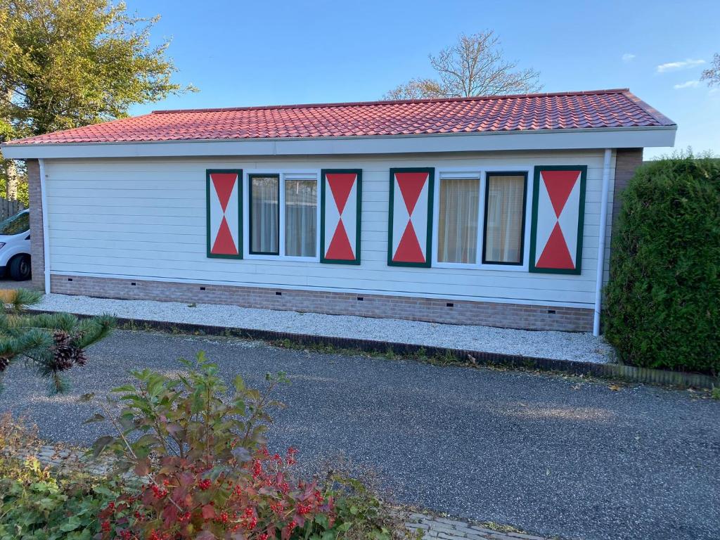 a small white house with red accents on it at de Zandput 46 in Zoutelande