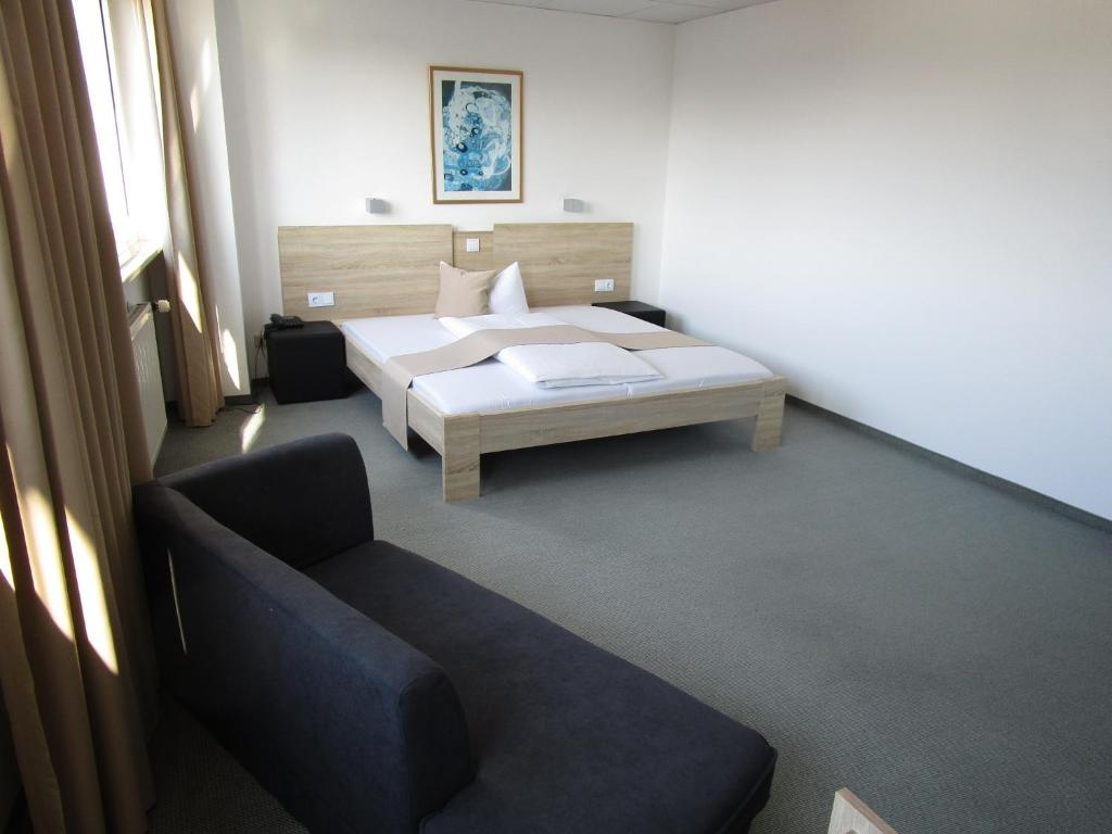 a bedroom with a bed and a couch at Businesshotel & Appartements Stuttgart-Vaihingen in Stuttgart