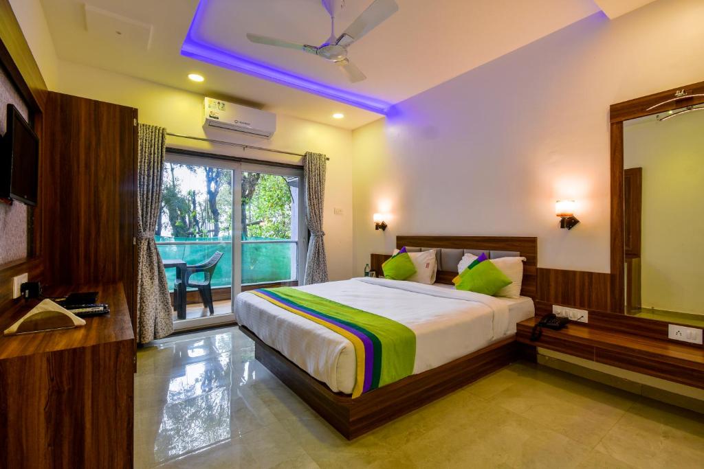 a bedroom with a bed and a mirror and a window at Treebo Trend Prince Palace in Mahabaleshwar